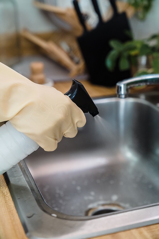 A Kiwi Clean Home cleaner disinfecting a sink